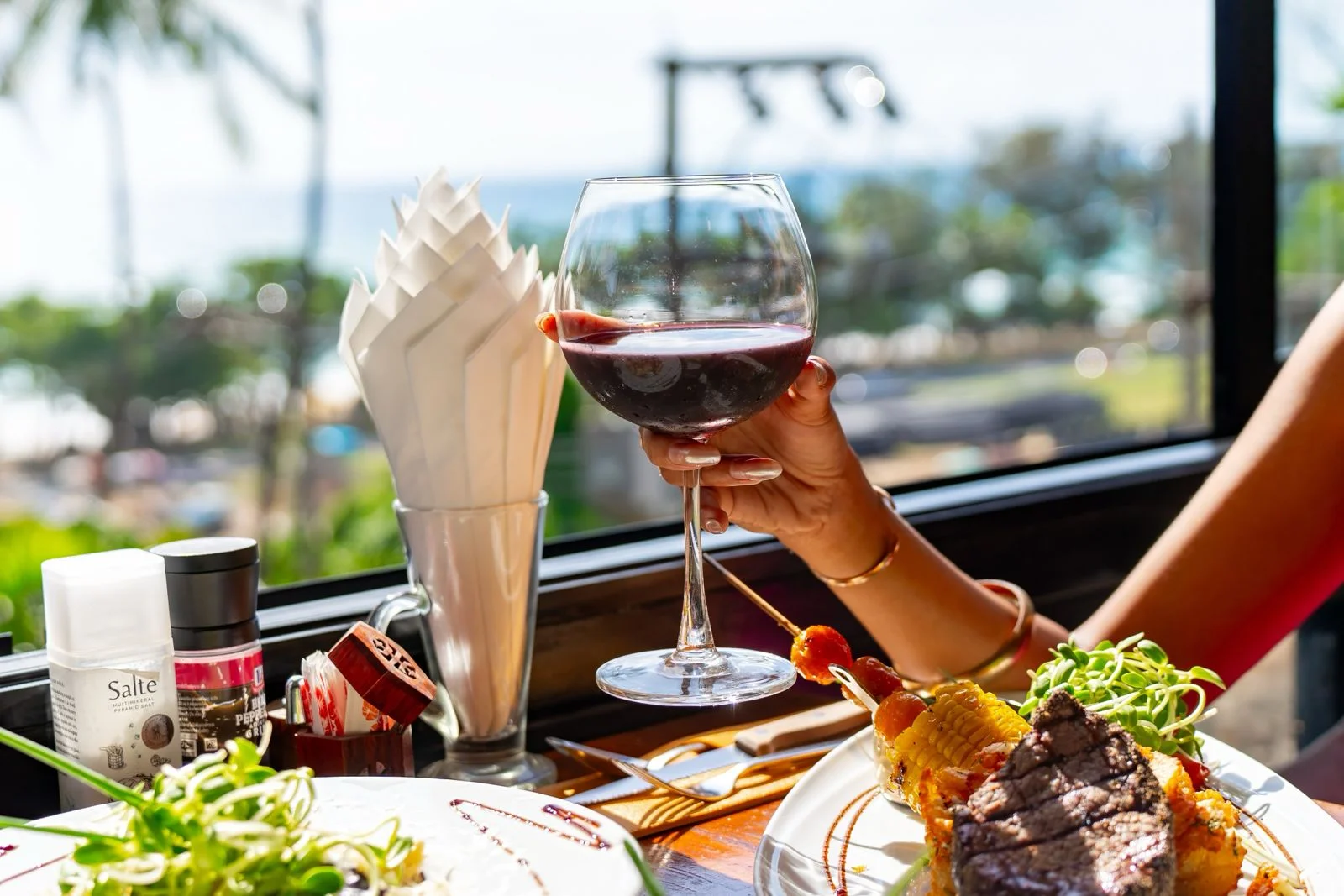 Original photograph of wine and steak beside the sea view at EAT Bar & Grill